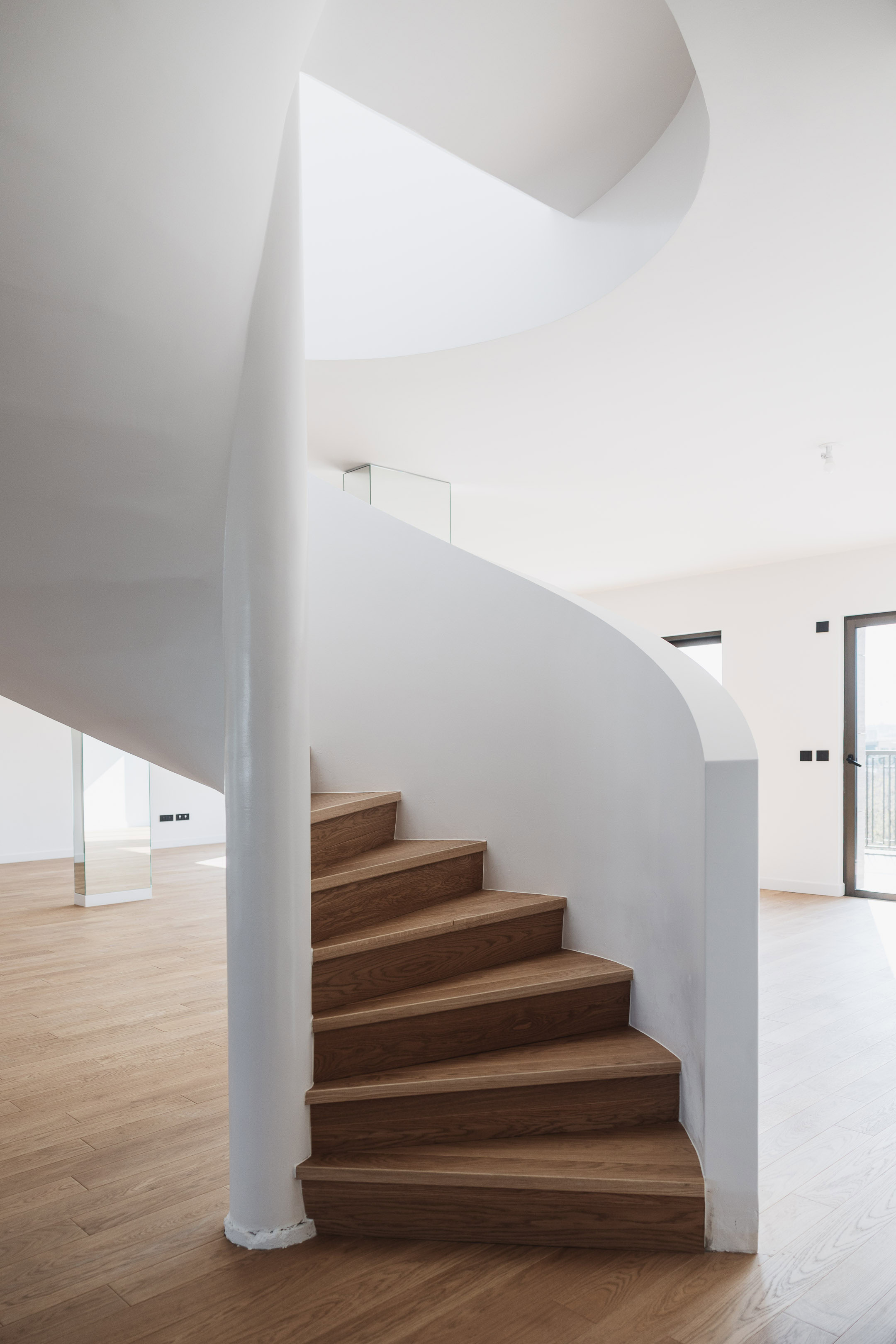 Escalier h&eacute;lico&iuml;dal design en bois et blanc dans un duplex de prestige, mettant en valeur l'architecture int&eacute;rieure contemporaine par maxime decarsin photographe