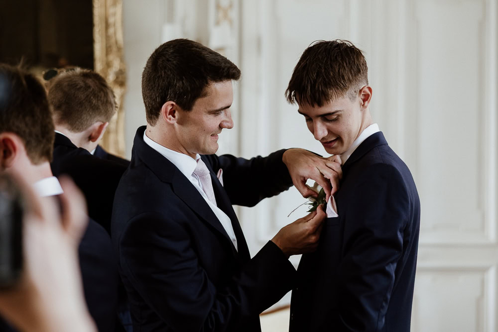 Le marié habit son frère lors d'un préparatif de mariage photographié par Maxime decarsin photographe