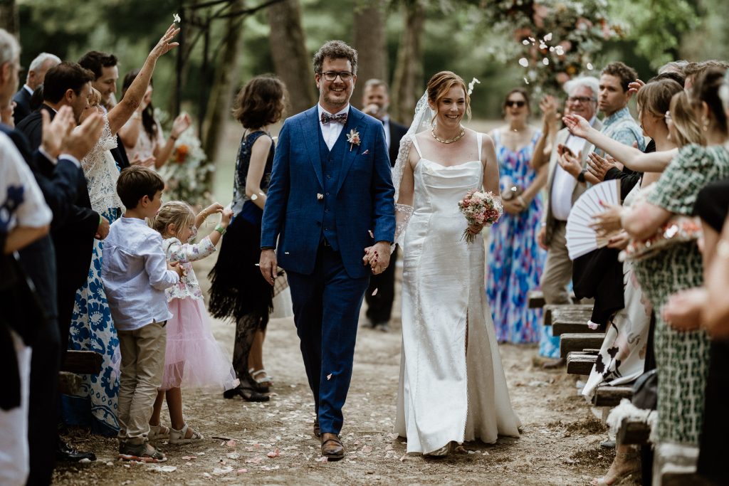 Un couple remonte l'allée d'une cérémonie laïque heureux Photographié par Maxime Decarsin photographe nomade