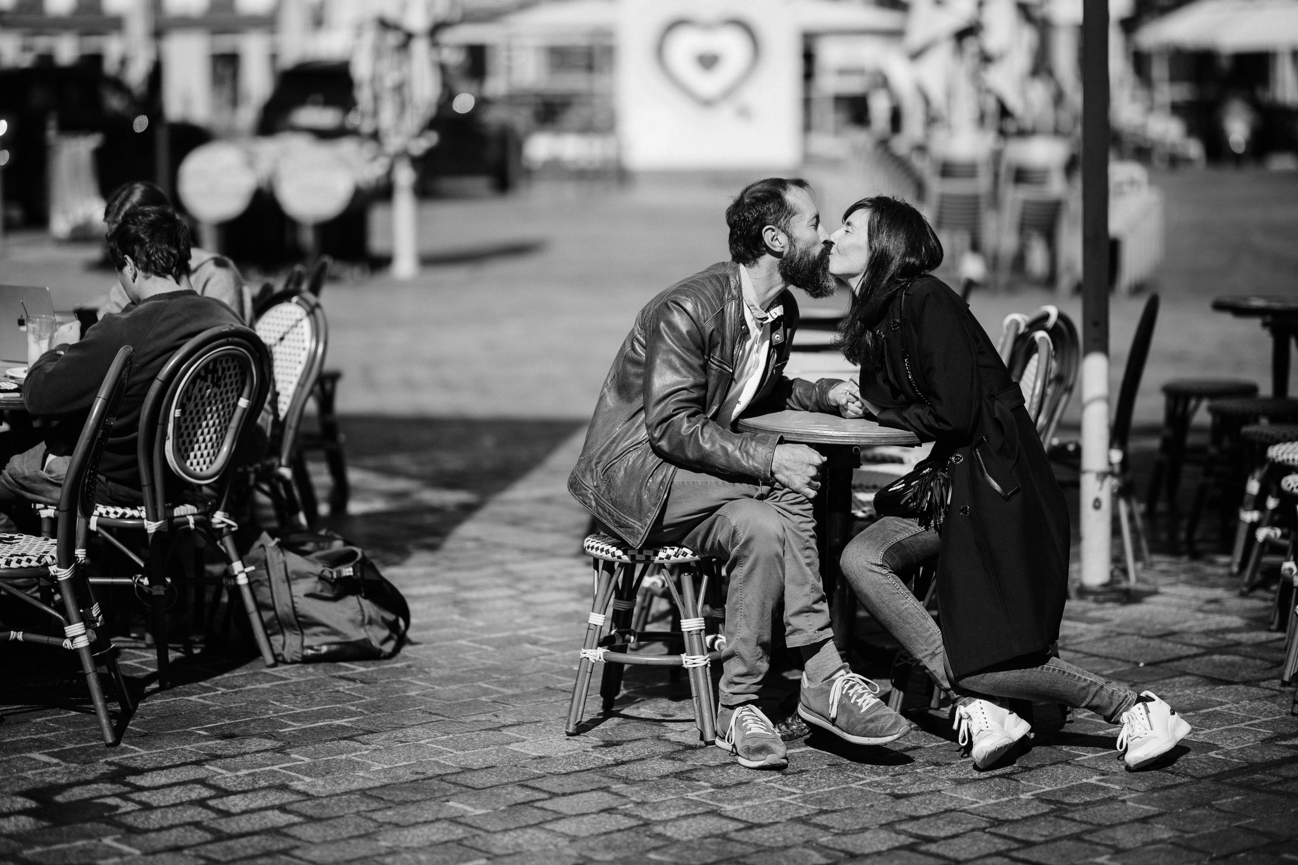 Photographie en noir et blanc D'un couple assis en terrasse d'un café par Maxime Decarsin photographe de mariage