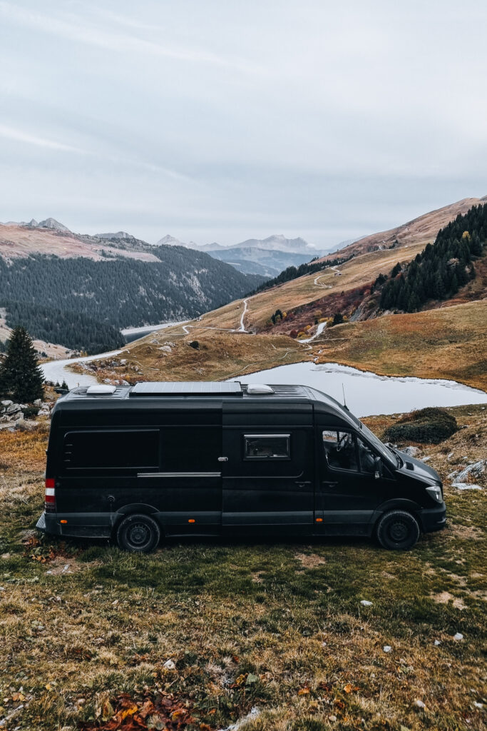 Le van noir de Maxime Decarsin garé en montagne, au-dessus d’un lac